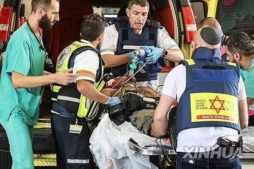 图为因巴勒斯坦武装派别哈马斯于7日发动的突袭而在以色列南部受伤的以色列男子被医护人员紧急护送的场景。【照片来源：新华社=韩联社】