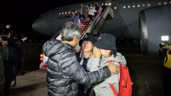 图为14日晚，通过京畿城南首尔机场回国的以色列韩侨走下KC-330(Signus)军用运输机后，正在和前来迎接的家人寒暄。【照片来源：NEWS1】