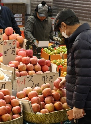 图为6日下午在首尔东大门区清凉里水果市场，一位市民正在挑选苹果。【照片来源：韩联社】