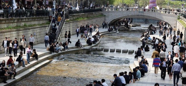 图为12日在韩国首尔清溪川，上班族们吃完午饭后享受着春日里的阳关。【照片来源：NEWS1】