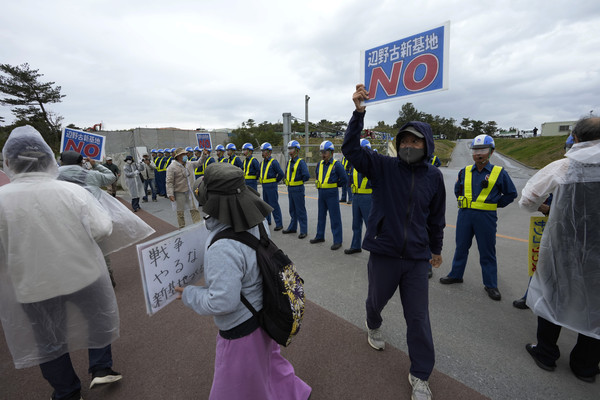 在日本冲绳县名护市，美国海军陆战队施瓦布营地附近，抗议者高举写有“反对边野古新基地”“停止战争，拒绝新基地建设”等标语的牌子，高呼口号，抗议基地建设。【照片来源：美联社】